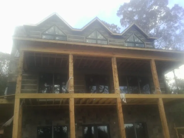 Dormers and porch framing on a large log home under construction — Roof Coating work by our crew in Helotes