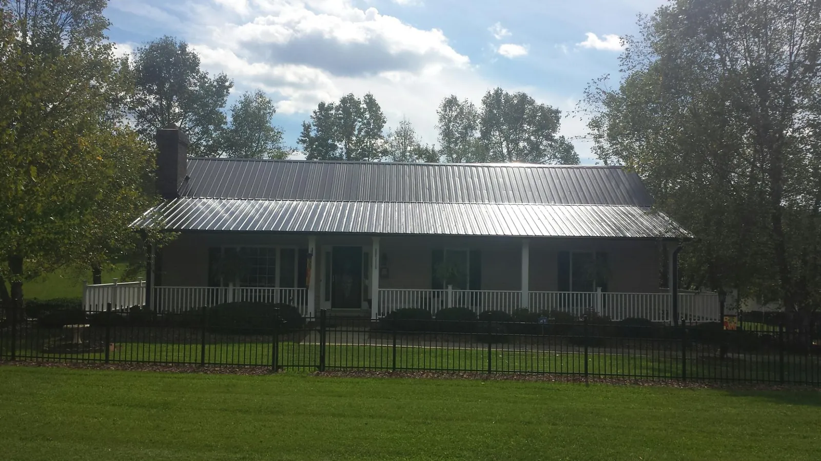 Gray metal roof on a brick ranch with a full width front porch — Gutter Guard Installation work by our crew in Helotes