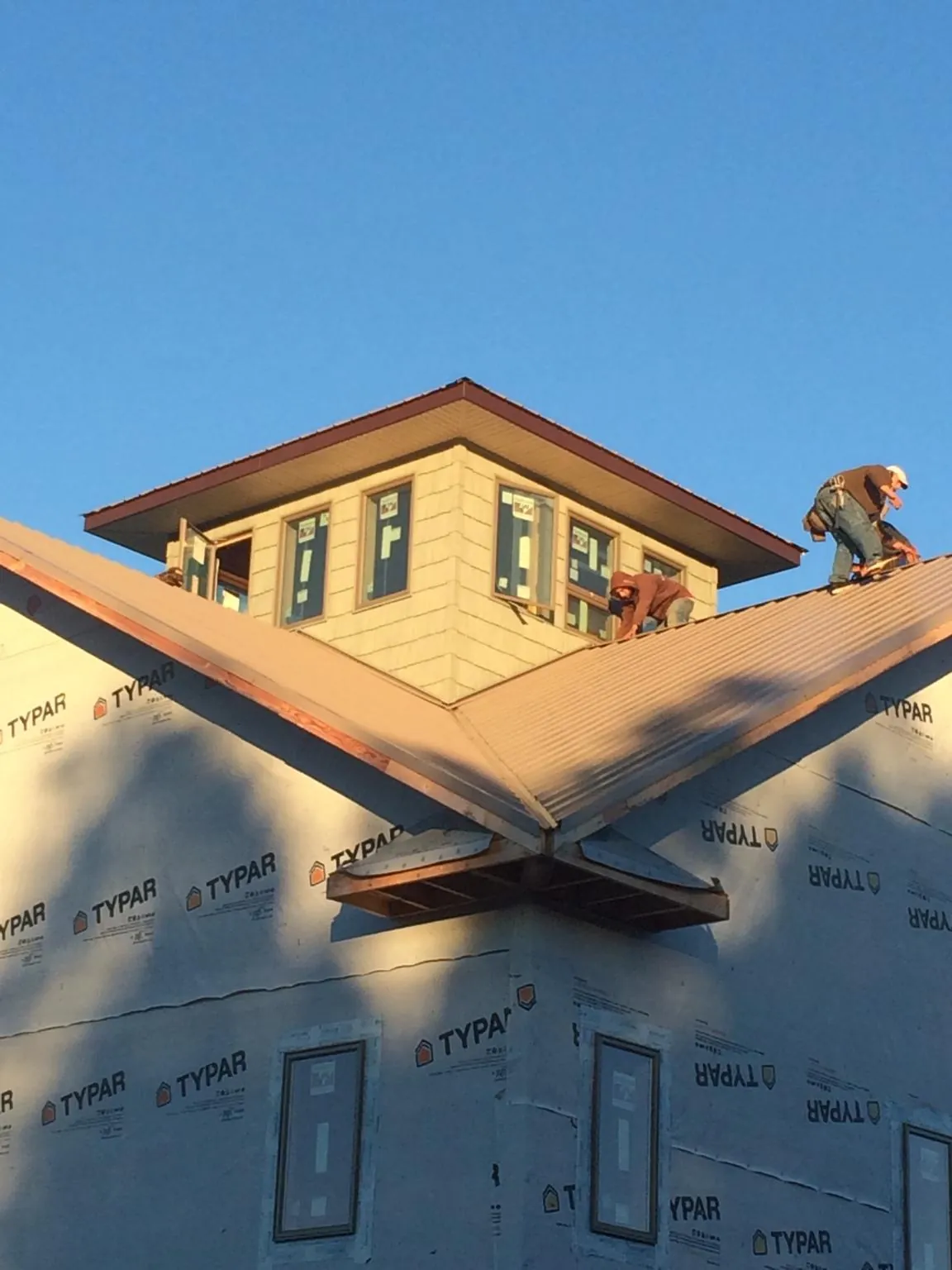 Roofers working around a rooftop cupola on a new metal roof at sunset — Roof Waterproofing in Helotes by Roofing Brothers